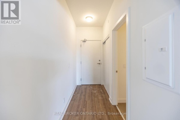 Interior hallway with wood-look laminate flooring and white walls. - 402 - 51 Clarington Boulevard, Clarington