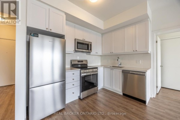 Close-up of white kitchen cabinets, stainless steel refrigerator, stove, and dishwasher. - 402 - 51 Clarington Boulevard, Clarington