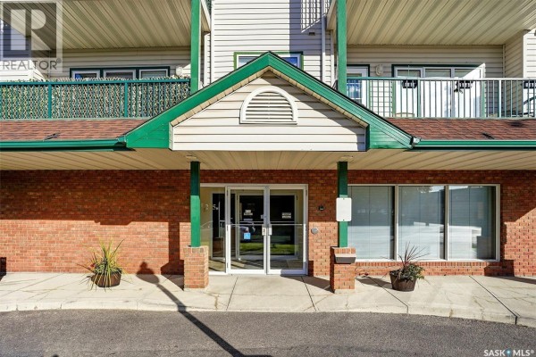 Front view of the apartment building with arched entrance and balconies on multiple floors. - 402 205 Mcintyre Street N, Regina