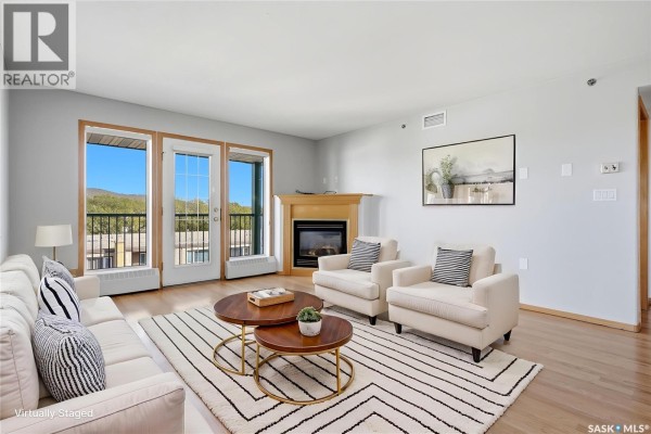 Interior entryway with a white door, coat rack, light fixture, and wood floors. - 402 205 Mcintyre Street N, Regina