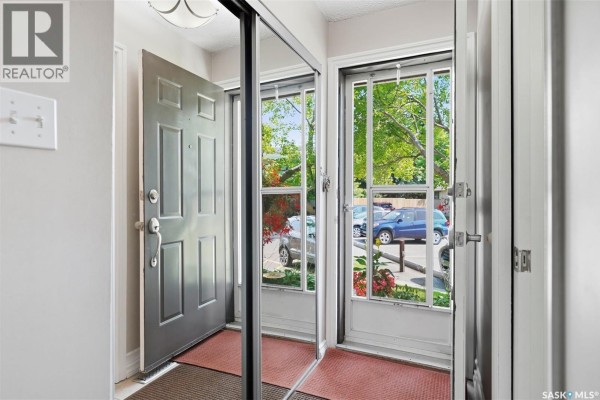 Interior view of a hallway with a dark grey front door and mirrored closet doors. - 402 2703 Spadina Crescent E, Saskatoon