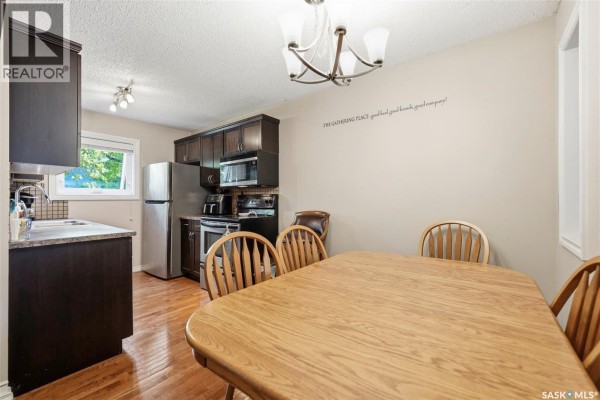 Kitchen and dining area with a wooden table, chairs, and dark wood cabinets. - 402 2703 Spadina Crescent E, Saskatoon