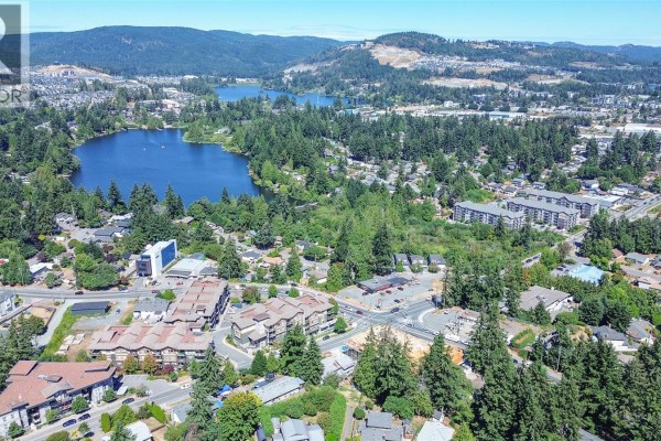 Aerial view of apartment buildings and a lake with surrounding suburban development. - 402 3210 Jacklin Rd, Langford