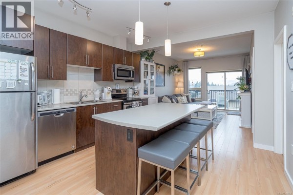 Living room with gray sofa, coffee table, and access to the balcony. - 402 3240 Jacklin Rd, Langford