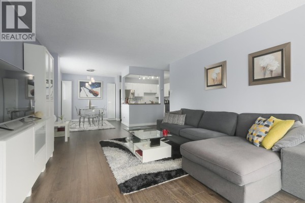 Living room, dining area, and kitchen with light purple walls and dark wood floors. - 402 550 Eighth Street, New Westminster