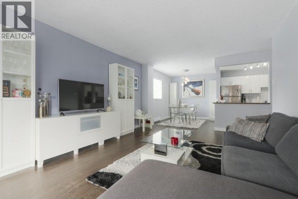 Living room with sectional sofa, view of dining area and kitchen with stainless steel appliances. - 402 550 Eighth Street, New Westminster