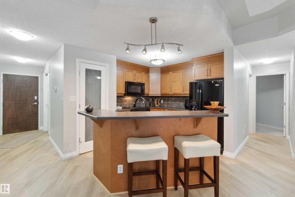 Open-concept living area with kitchen, dining space, and large windows. - #402 9020 Jasper Av Nw, Edmonton