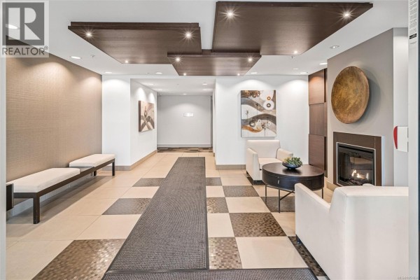 Building lobby with a fireplace, seating area, artwork, and tiled floor. - 402 999 Burdett Ave, Victoria