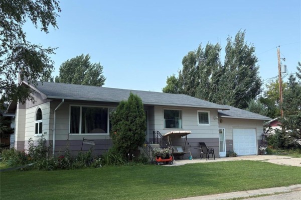 Front view of a beige and grey split-level house with a garage and green lawn. - 402 Buchanon Avenue, Dauphin
