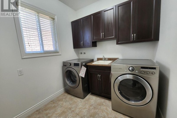 Modern laundry room with front-loading washer, dryer, and utility sink - 402 Palamino Place Waterloo