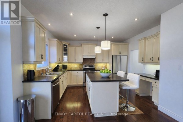 Modern kitchen with island, hardwood floors, stainless appliances, recessed lighting - 402 Palamino Place, Waterloo