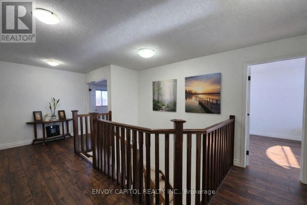 Dark hardwood floors, wooden railing, and staircase in a renovated upper hallway - 402 Palamino Place, Waterloo