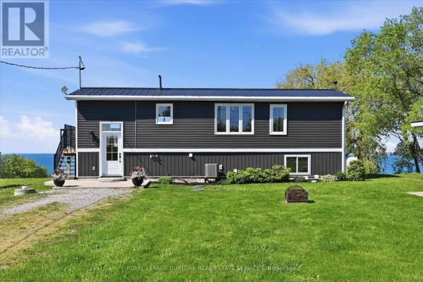 Front exterior of a dark grey house with white trim and large windows. - 402 South Coast Drive, Haldimand