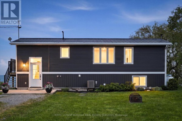 Exterior of a dark grey house at dusk with illuminated windows. - 402 South Coast Drive, Haldimand
