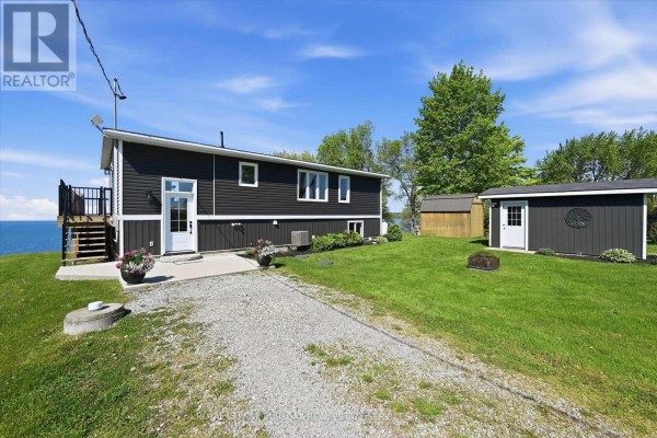 Side exterior of a dark grey house with a gravel driveway and shed. - 402 South Coast Drive, Haldimand
