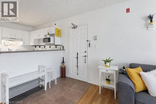 Entrance hallway with a white door, shoe rack, small table, and view of a kitchen counter. - 4025 Kilmer Drive Unit# 310, Burlington
