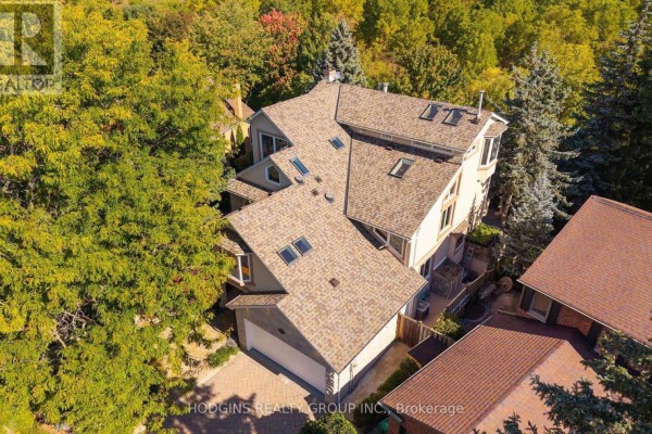 Aerial view of a house with a complex roofline, skylights, and surrounded by mature trees. - 4028 Powderhorn Court, Mississauga