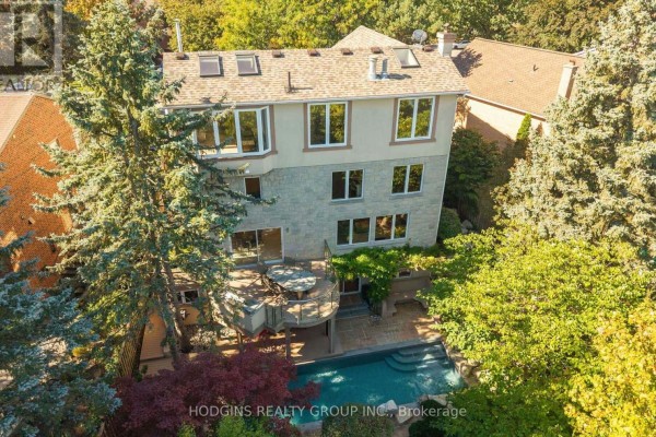 Rear exterior view of a house with a pool, deck, and lush green trees. - 4028 Powderhorn Court, Mississauga