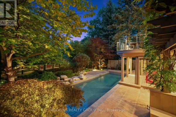Backyard with a swimming pool, patio, deck, and mature landscaping at dusk. - 4028 Powderhorn Court, Mississauga
