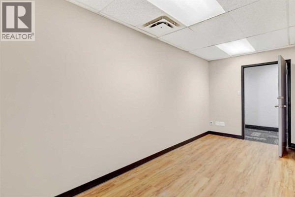 Interior view of an empty office space with light wood laminate flooring and closed door. - 403, 9728 101 Avenue, Grande Prairie