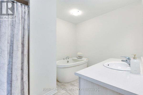 Bathroom with a white oval bathtub, vanity with sink, and marble-patterned shower curtain. - 403 - 1148 Dragonfly Ave Avenue, Pickering