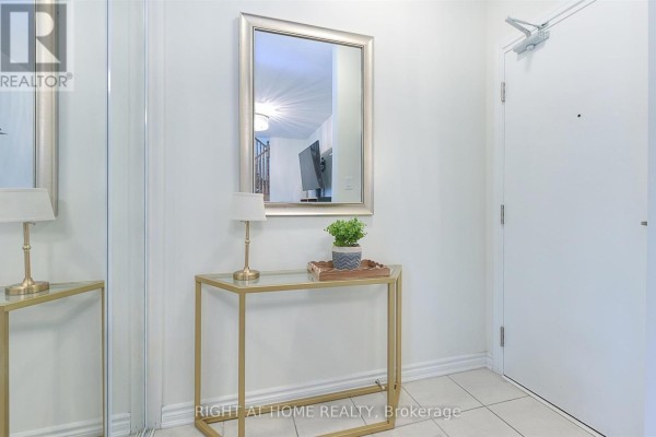 Entrance hallway with a console table, mirror, lamp, and door. - 403 - 1148 Dragonfly Ave Avenue, Pickering