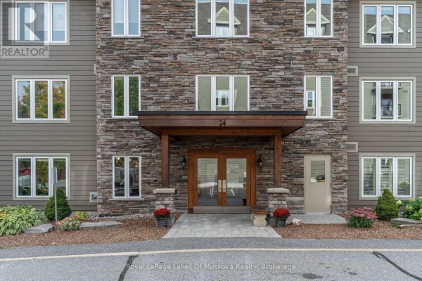 Entrance to the apartment building at 24 Dairy Lane with double glass doors and stone pillars. - 403 - 24 Dairy Lane, Huntsville
