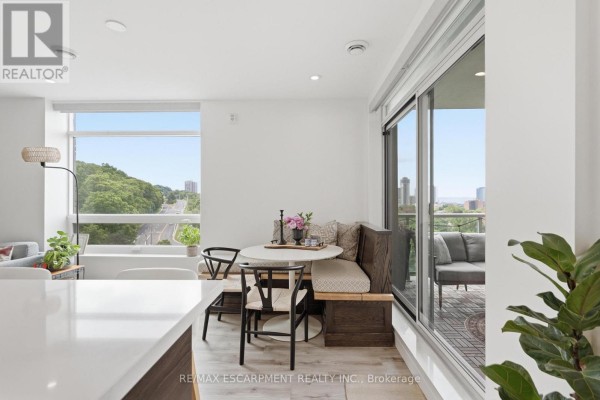Dining nook with built-in seating, small table, and large windows overlooking a city street. - 403 - 455 Charlton Avenue E, Hamilton