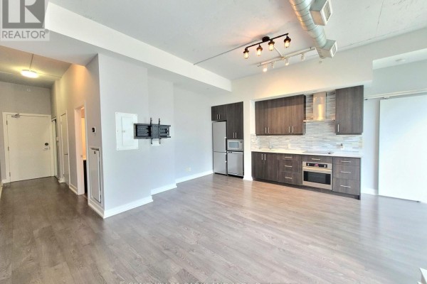 Open concept living area with modern kitchen featuring dark wood cabinets and stainless steel appliances. - 403 - 75 The Donway W, Toronto
