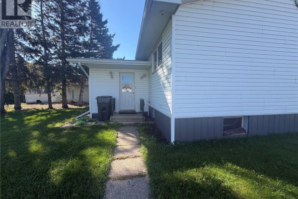 Concrete walkway leading to the back door of the white vinyl-sided bungalow. - 403 & 401 Main Street, Pelly