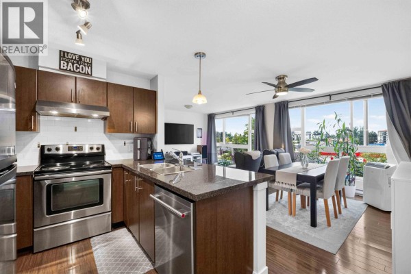 Open concept living space with a modern kitchen, dining area, and living room with large windows. - 403 12075 228 Street, Maple Ridge