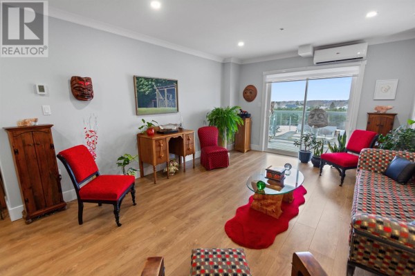 Cozy seating area with red chairs, decorative plants, and artwork on the walls - 403 18 Gilbert Drive, Charlottetown