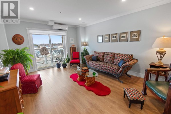 Living room featuring a patterned sofa, coffee table, and access to a balcony - 403 18 Gilbert Drive, Charlottetown