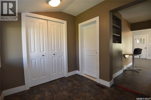 View from hallway showing a doorway, closet, built-in shelves, and an opening to another room. - 403 2nd Street W, Nipawin