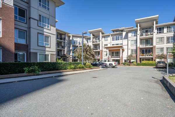 Exterior view of apartment building with parked cars and a paved lot. - 403 3192 Gladwin Road, Abbotsford
