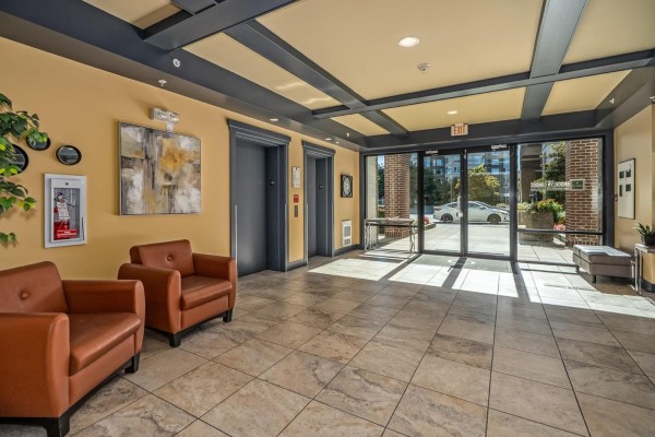 Apartment building lobby with two elevators, seating, and tiled floors. - 403 3192 Gladwin Road, Abbotsford