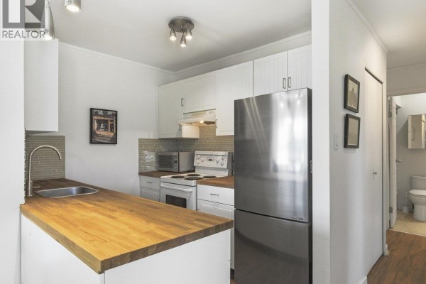 Living and dining area with wood floors, a bookcase, and a table with chairs. - 403 570 E 8th Avenue, Vancouver