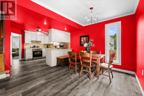 Dining area and kitchen with red walls, wooden table, and white cabinets - 403 Alfred Street Pembroke