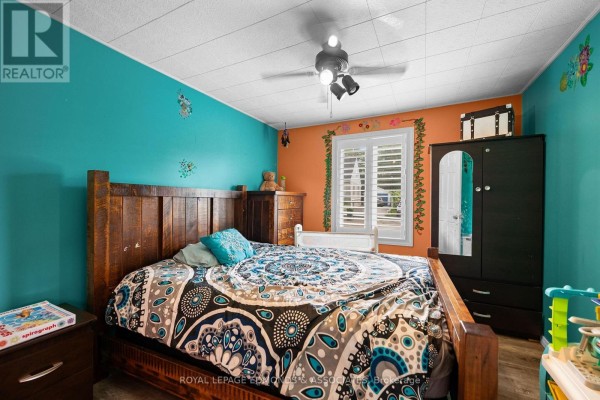 Bedroom with teal and orange walls, wooden bed frame, and mirrored wardrobe - 403 Alfred Street Pembroke