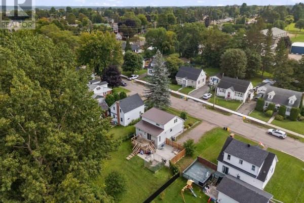 Aerial view of houses on a tree-lined street with a fenced yard, pool, and play structure - 403 Alfred Street Pembroke