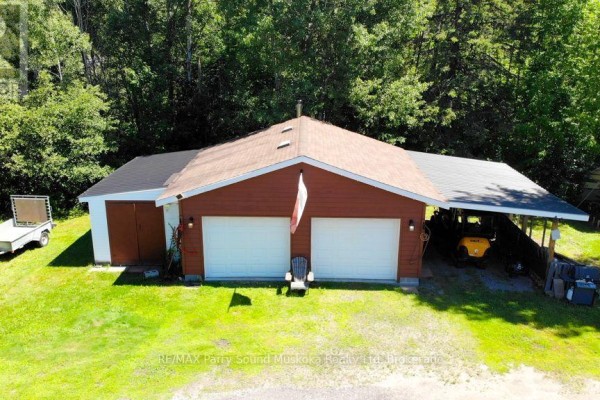 Aerial view of two residential buildings and a detached garage on a green property with a lake in the distance. - 4031 Highway 520 Highway, Magnetawan