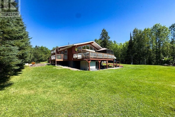 Aerial view of a detached garage with two white garage doors, a covered carport, and a storage shed. - 4031 Highway 520 Highway, Magnetawan