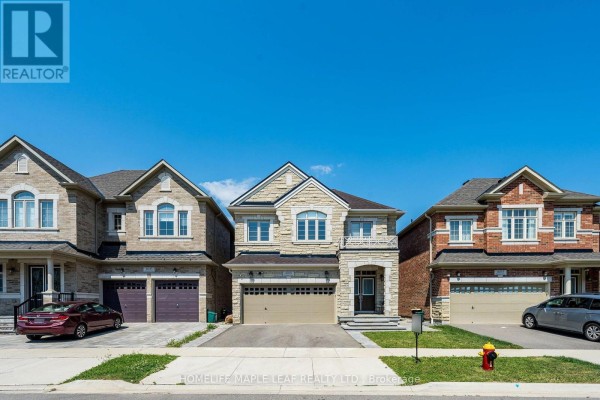 Front exterior of a detached house with stone facade and double garage doors. - 4039 Eternity Way, Oakville