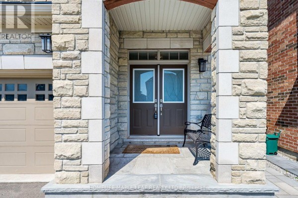 Covered front entryway with double doors, stone pillars, and a black metal bench. - 4039 Eternity Way, Oakville