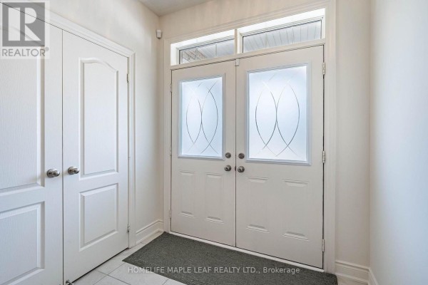 Interior view of a bright foyer with white double doors and closet doors. - 4039 Eternity Way, Oakville