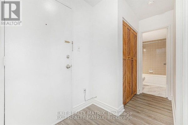 Interior hallway with a white door, wood-paneled closet, and view into a bathroom. - 403c - 2041 Arrowsmith Drive, Ottawa