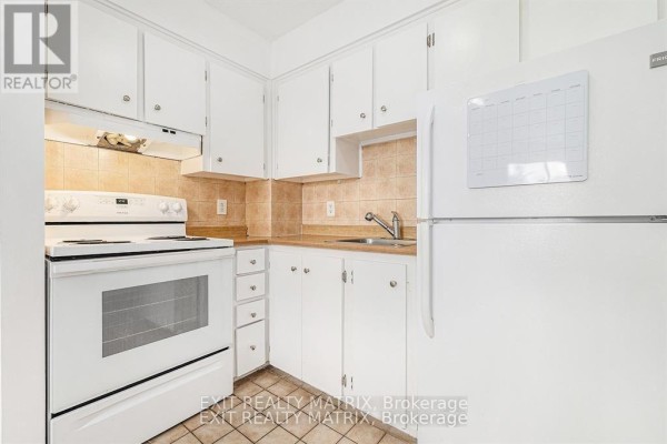 Close-up view of a white kitchen with white cabinets, tiled backsplash, and appliances. - 403c - 2041 Arrowsmith Drive, Ottawa