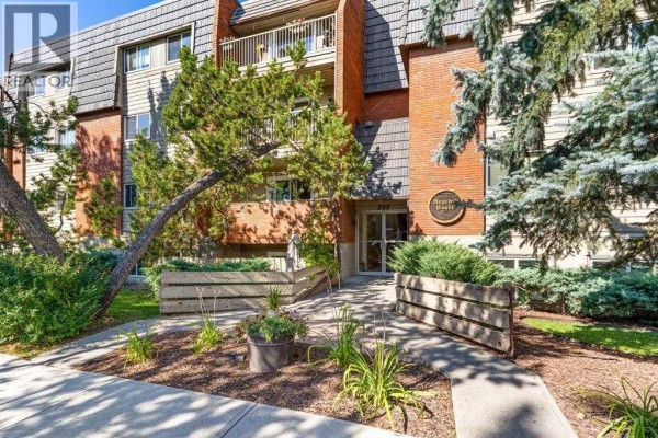 Exterior view of the Mariner's Court apartment building with trees and landscaping. - 404, 222 5 Avenue Ne, Calgary