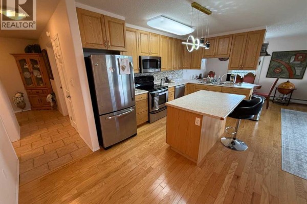 Kitchen with light wood cabinets, stainless steel appliances, and a central island. - 404, 228 Pembina Avenue, Hinton