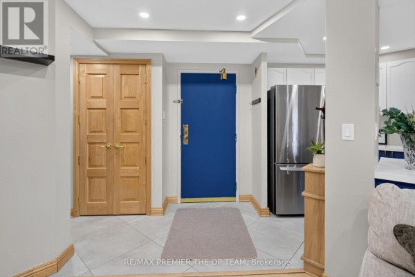 Hallway with a blue front door, stainless steel refrigerator, and wooden double doors. - 404 - 100 Arbors Lane, Vaughan